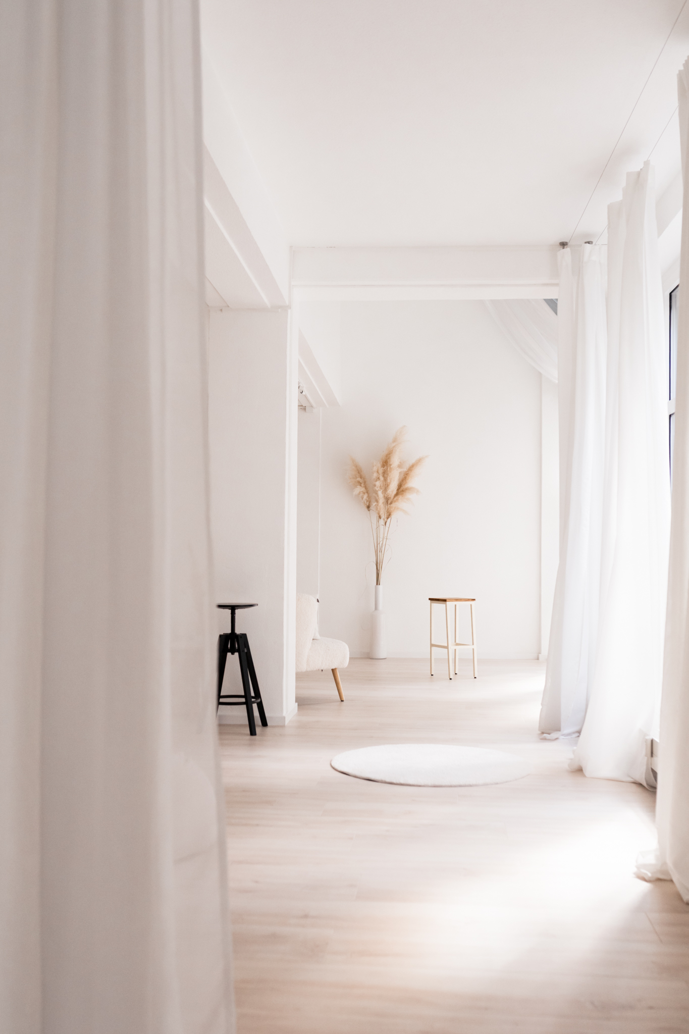 Blick vom fernen Ende des Studios durch die gesamte Länge. Ein schwarzer Hocker und etwas Pampasgras stehen dort.